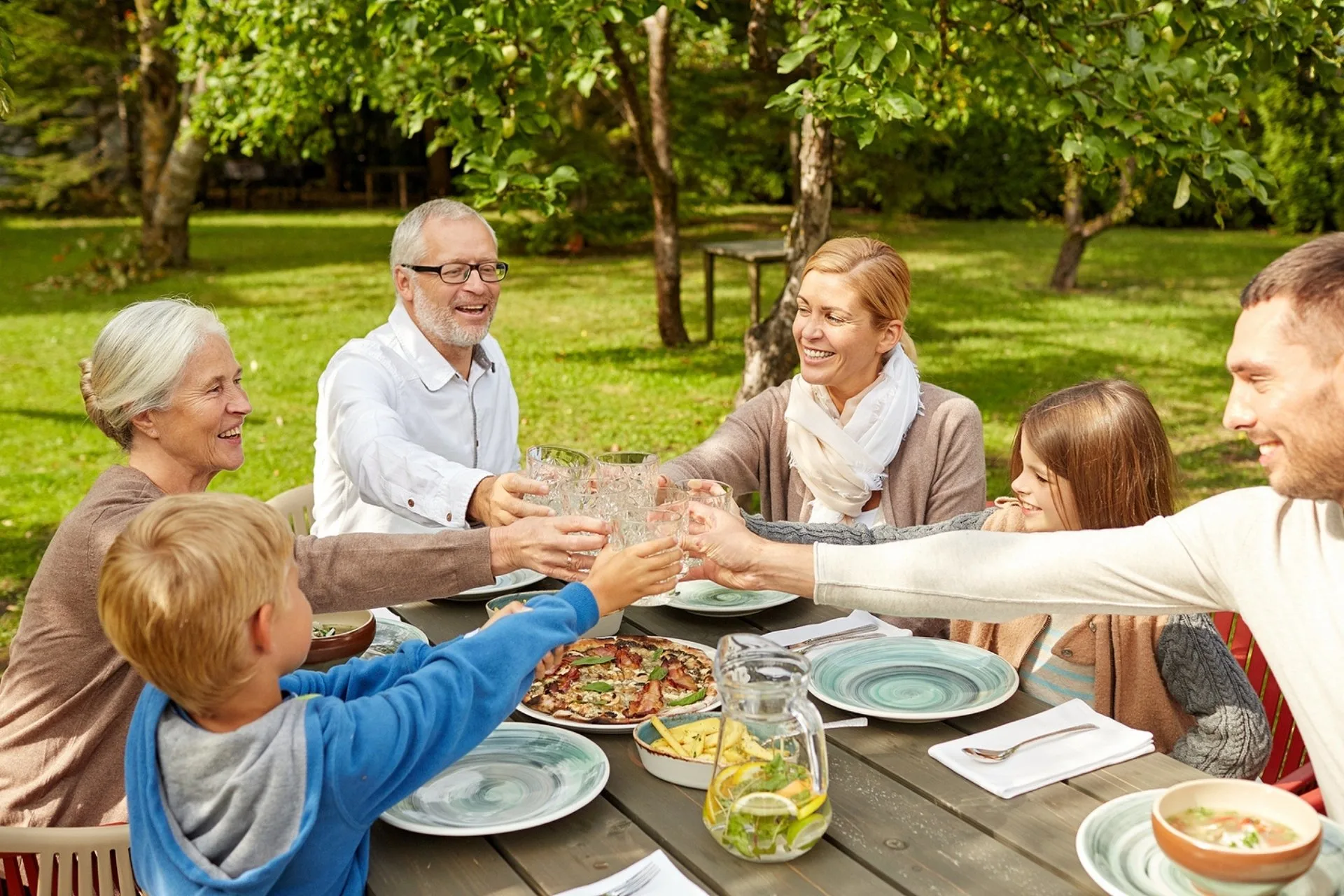Family enjoying a meal together outdoors during a sunny afternoon